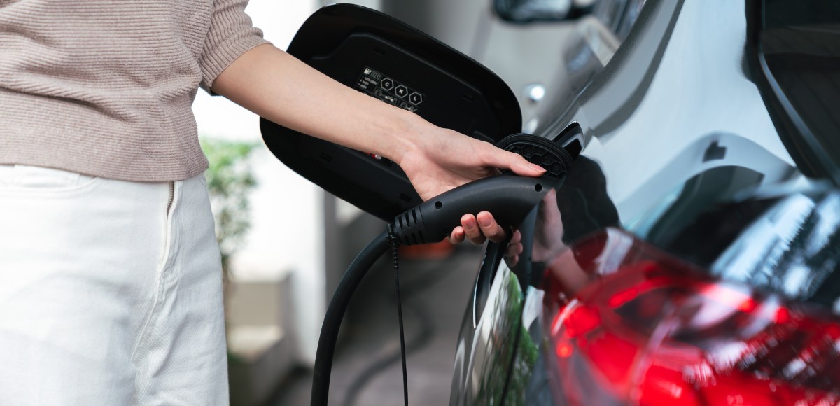 Mujer cargarndo su auto eléctrico