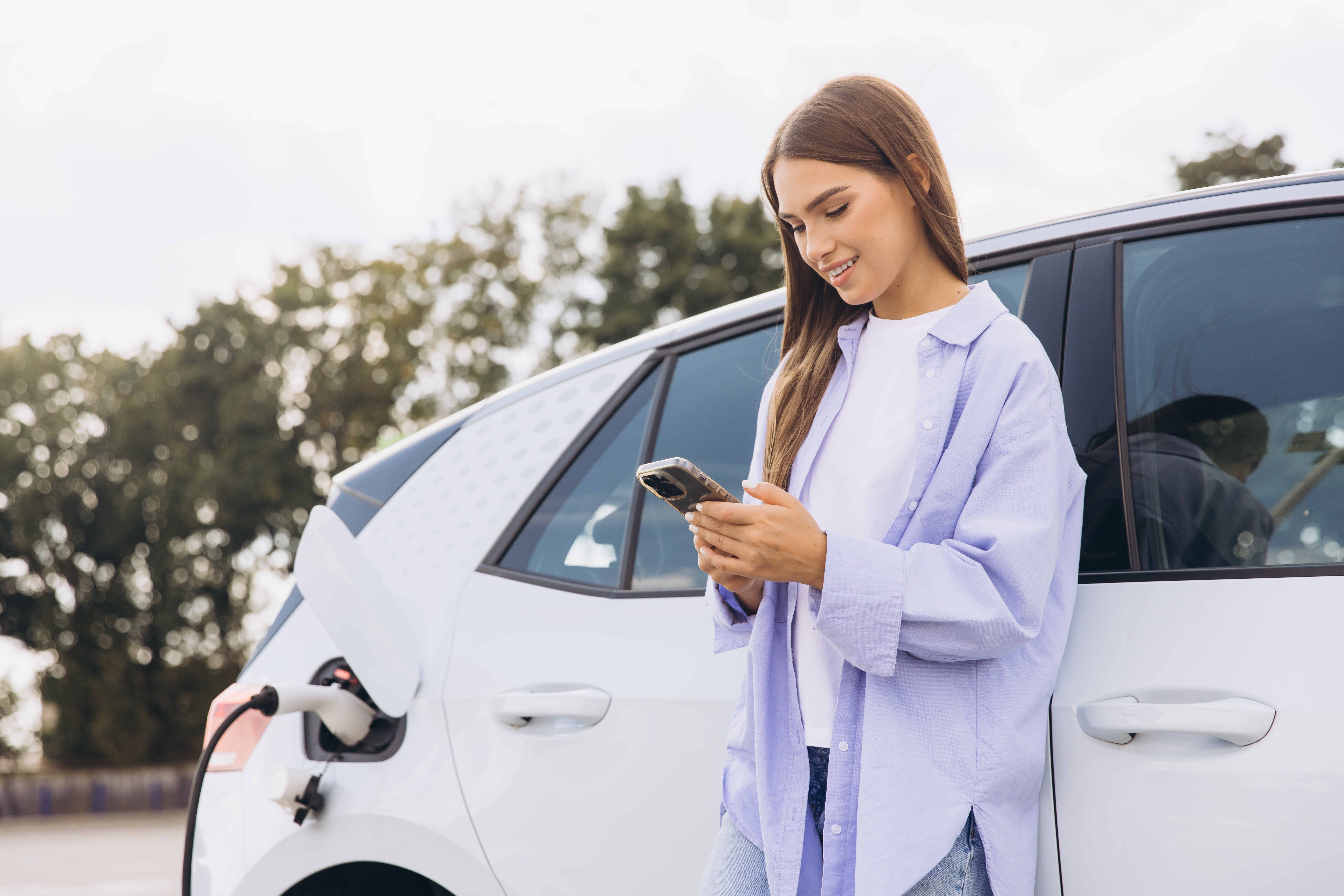 Chica esperando mientras se carga el cohe eléctrico