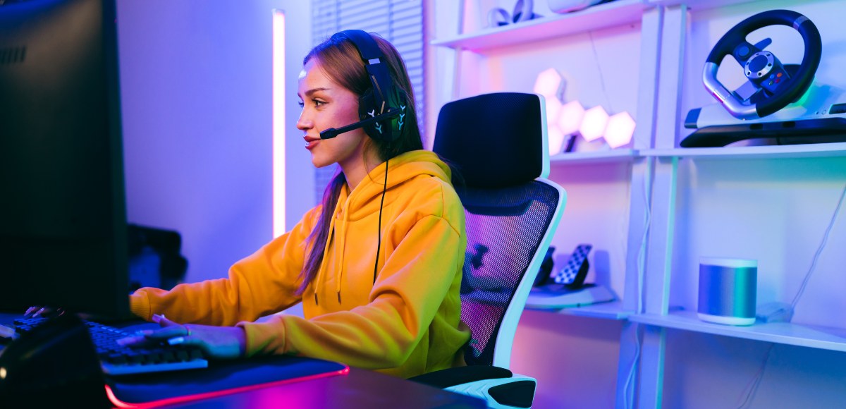 Chica gamer sentada jugando delante del ordenador