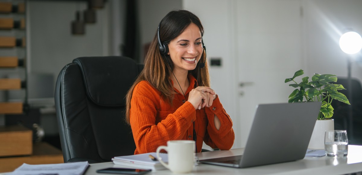 Mujer con sonriendo y viendo la pantalla del ordenador